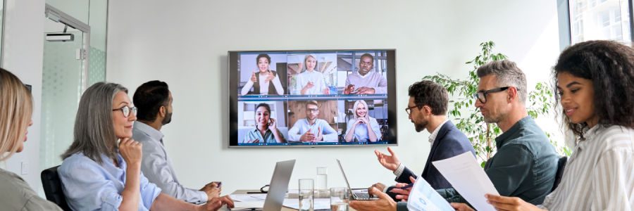 IT leaders sit around a conference table to plan a cloud migration while others join remotely on camera