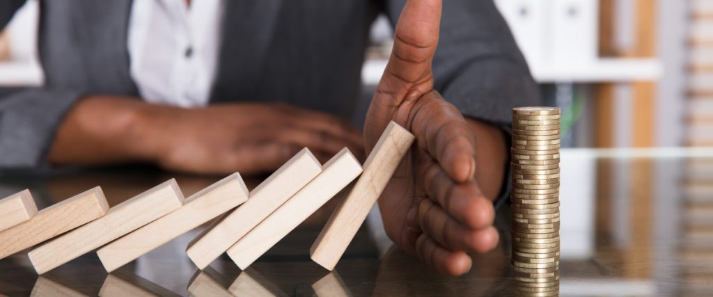 hand stopping dominoes from falling to represent how a disaster recovery plan prevents major losses